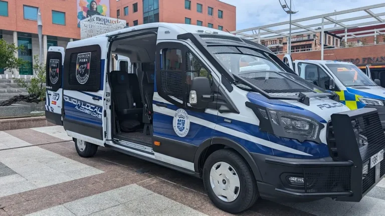 Una furgoneta blanca y azul de la Policía Local, con las puertas laterales abiertas revelando el interior, estacionada en una plaza urbana.