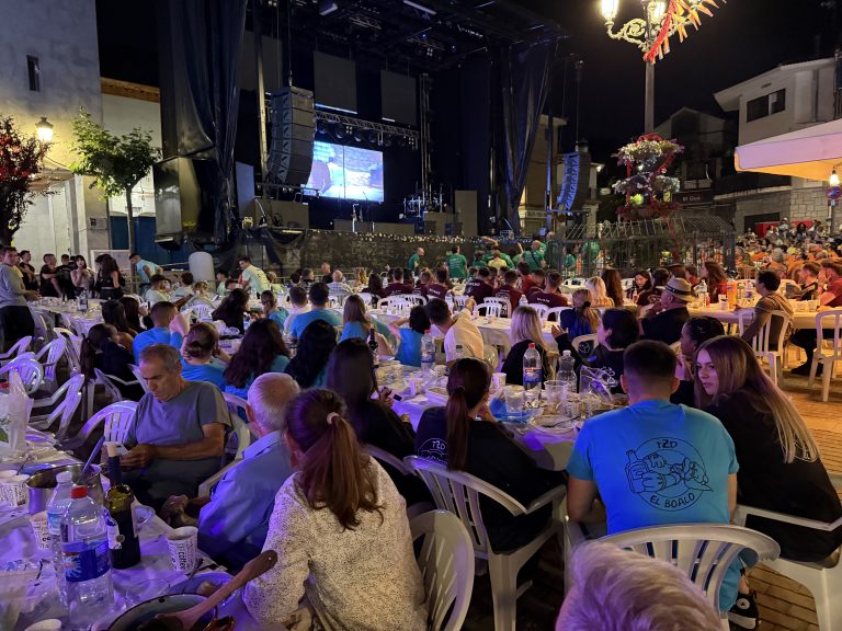 Gran Cena de Hermandad en las Fiestas de El Boalo 2025, con mesas llenas de vecinos disfrutando bajo el escenario de un concierto.